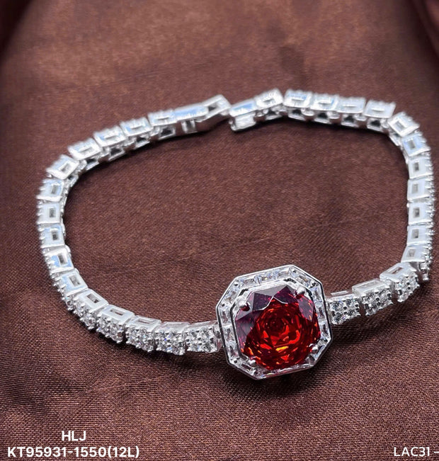 Silver bracelet with a red gemstone on a brown fabric background