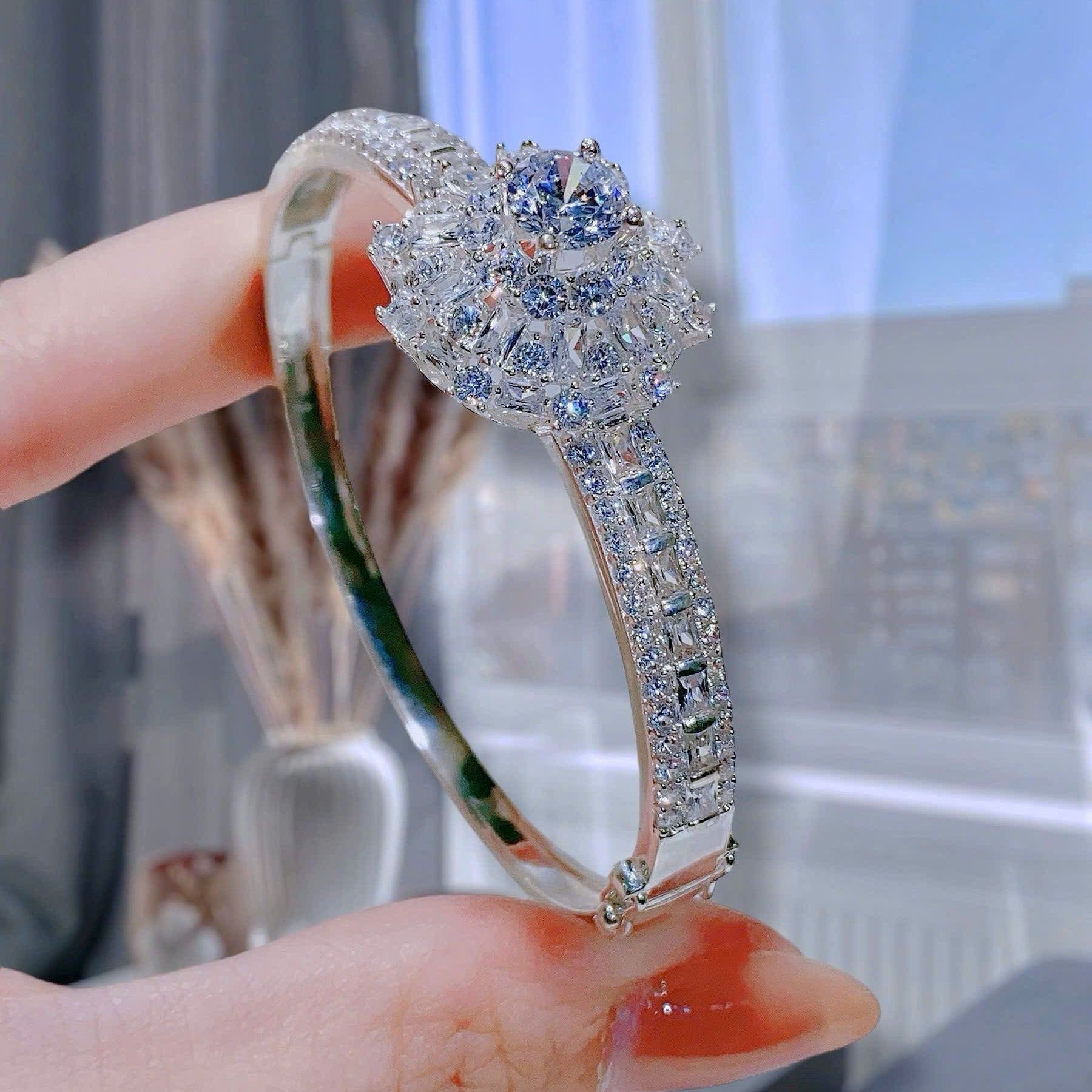 Silver bracelet with blue gemstones held by a hand against a blurred indoor background