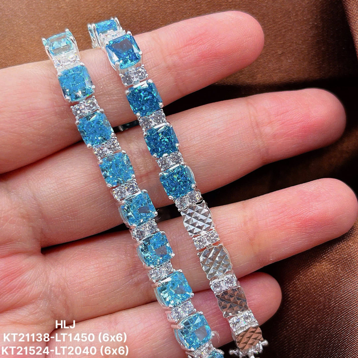 Silver bracelet with blue gemstones held on a hand against a brown background