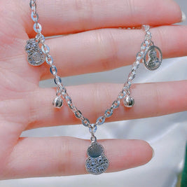 Silver bracelet with charms held in a hand against a neutral background