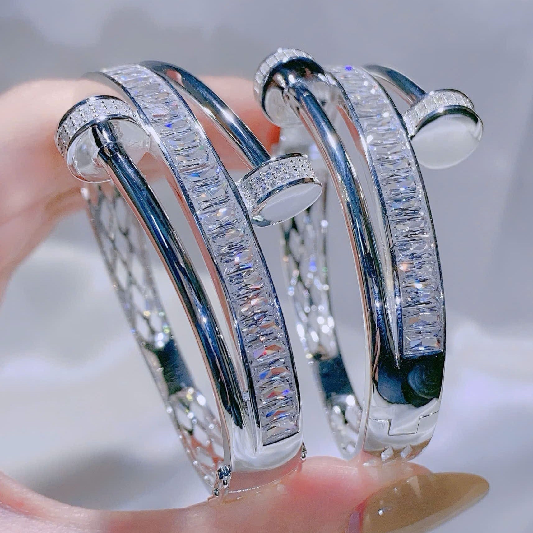 Silver bracelet with diamond accents on a hand against a neutral background