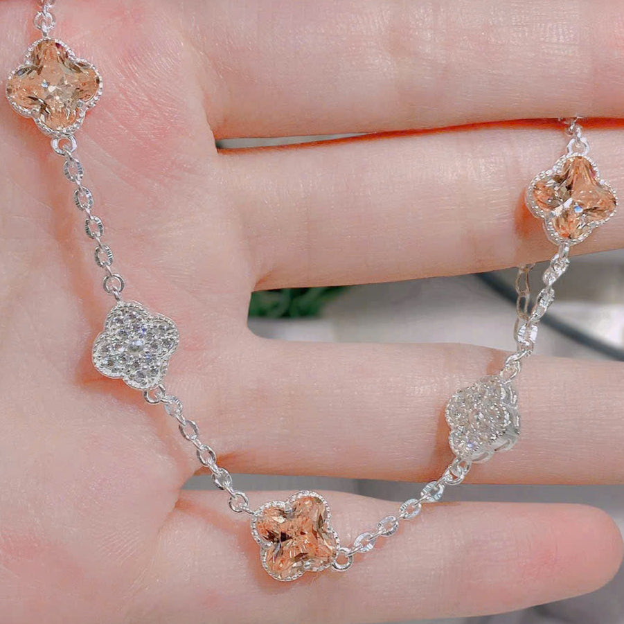 Silver bracelet with floral designs on a hand against a neutral background