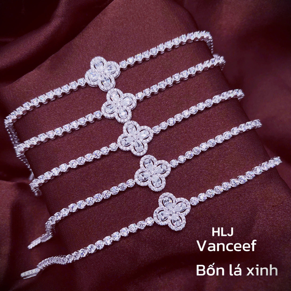 Silver bracelet with floral designs on a maroon fabric background, featuring the brand HLJ Vanceef.