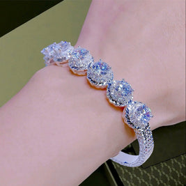 Silver bracelet with gemstones on a wrist against a neutral background