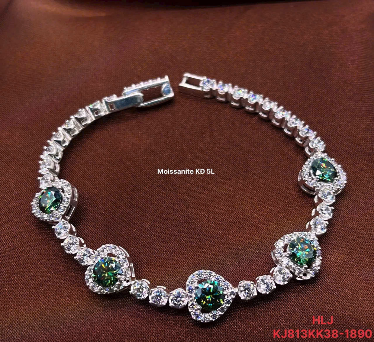 Silver bracelet with green and clear gemstones on a brown background