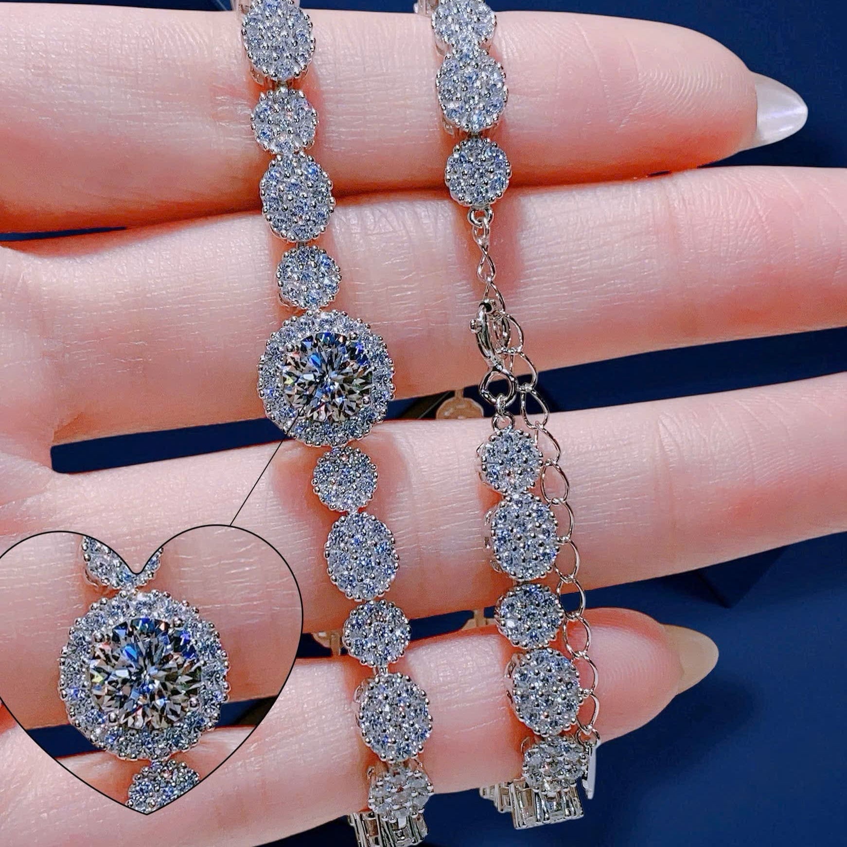 Silver bracelet with round gemstones held by a hand against a blue background