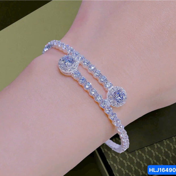 Silver bracelet with round stones on a wrist against a green background