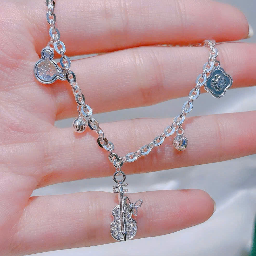 Silver chain bracelet with heart-shaped charms held in a hand against a blurred background