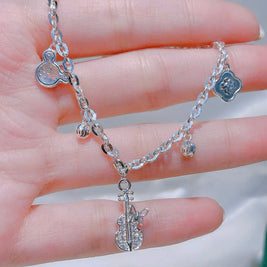 Silver chain bracelet with heart-shaped charms held in a hand against a blurred background