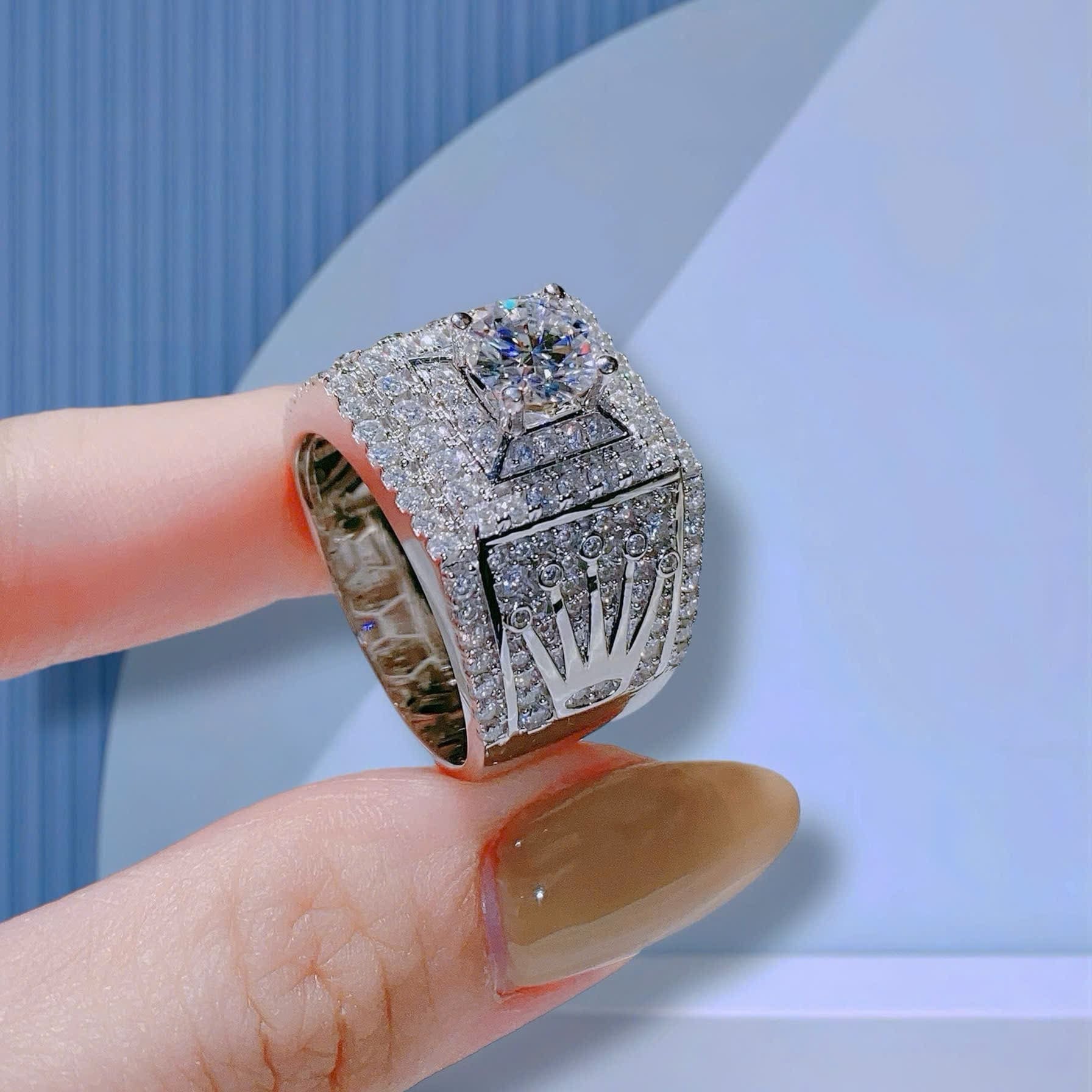 Silver championship ring with gemstones on a finger against a light blue background