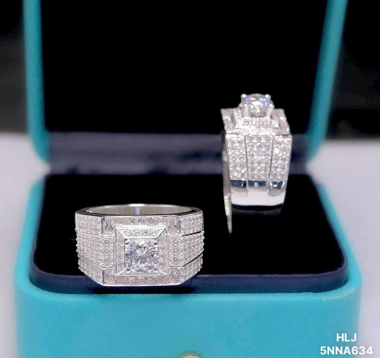 Silver diamond ring and earring set on a turquoise stand with a blurred background