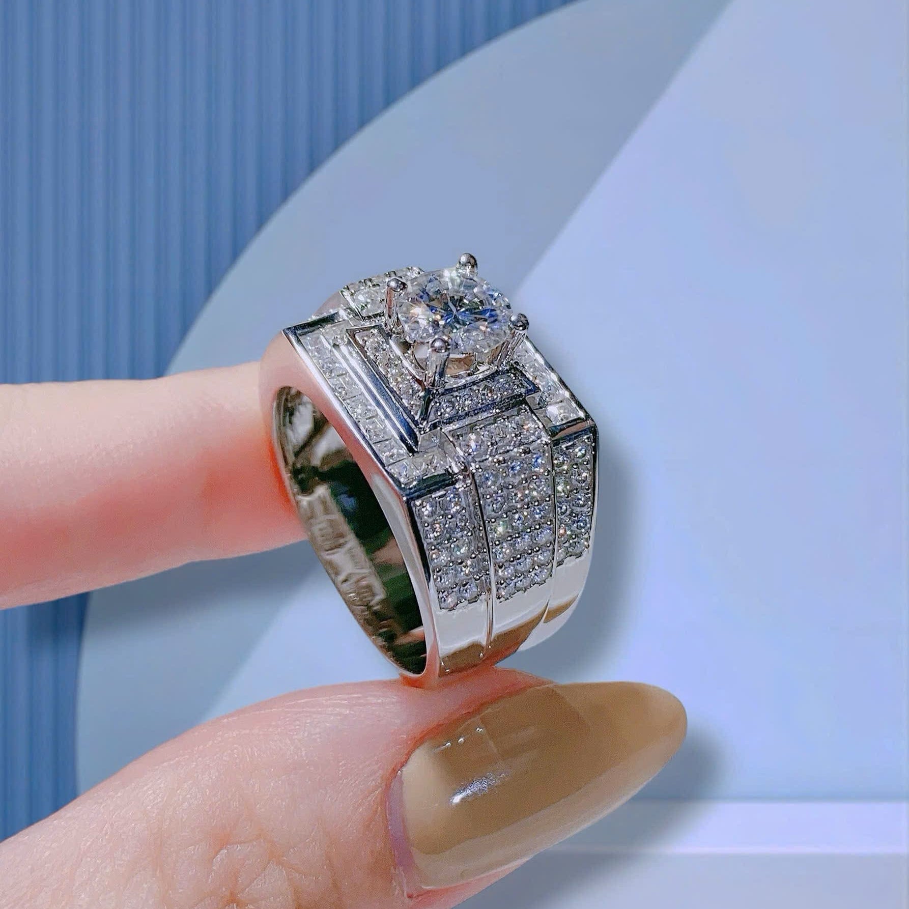 Silver diamond ring on a hand with a light blue background