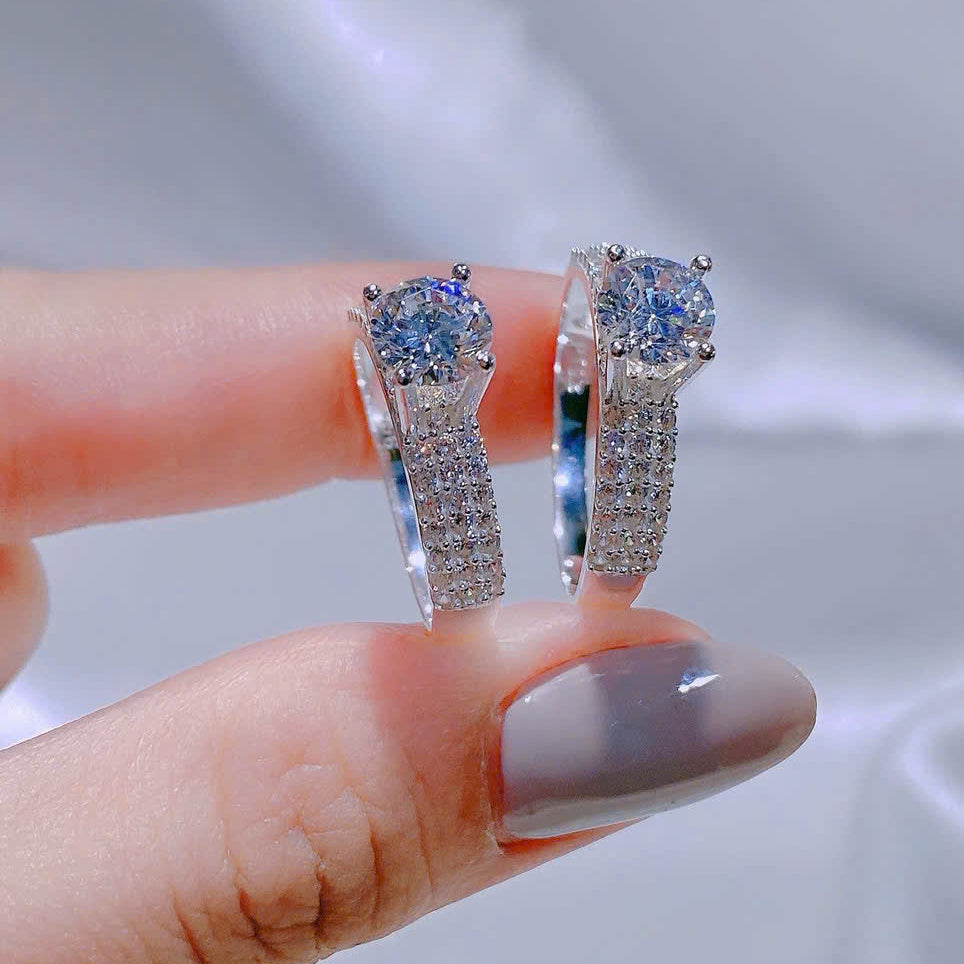 Silver earrings with blue gemstones held between fingers against a neutral background