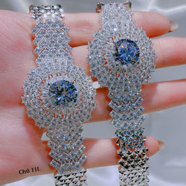 Silver earrings with blue gemstones held in hand against a neutral background