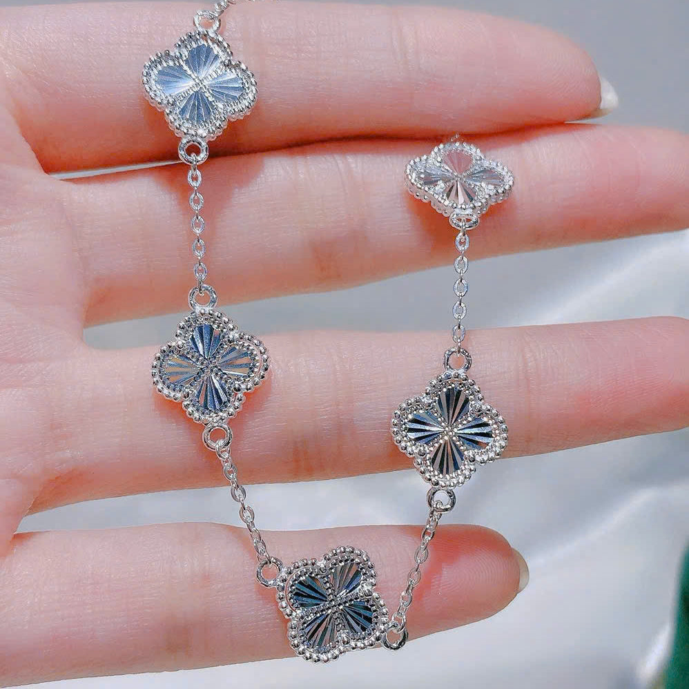 Silver earrings with floral designs held on a hand against a neutral background
