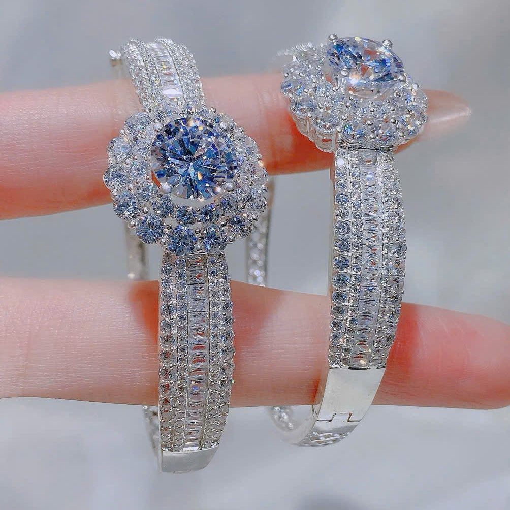 Silver earrings with gemstones held between fingers against a neutral background