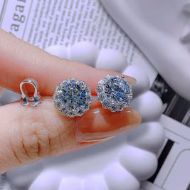 Silver earrings with gemstones held between fingers on a newspaper background