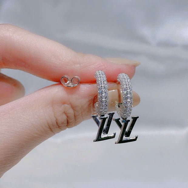 Silver hoop earrings held by a hand with a blurred background