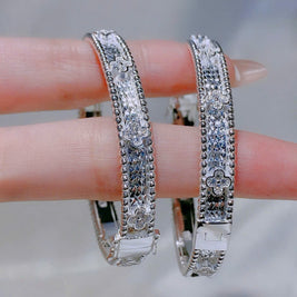 Silver hoop earrings with clear stones on a blurred background