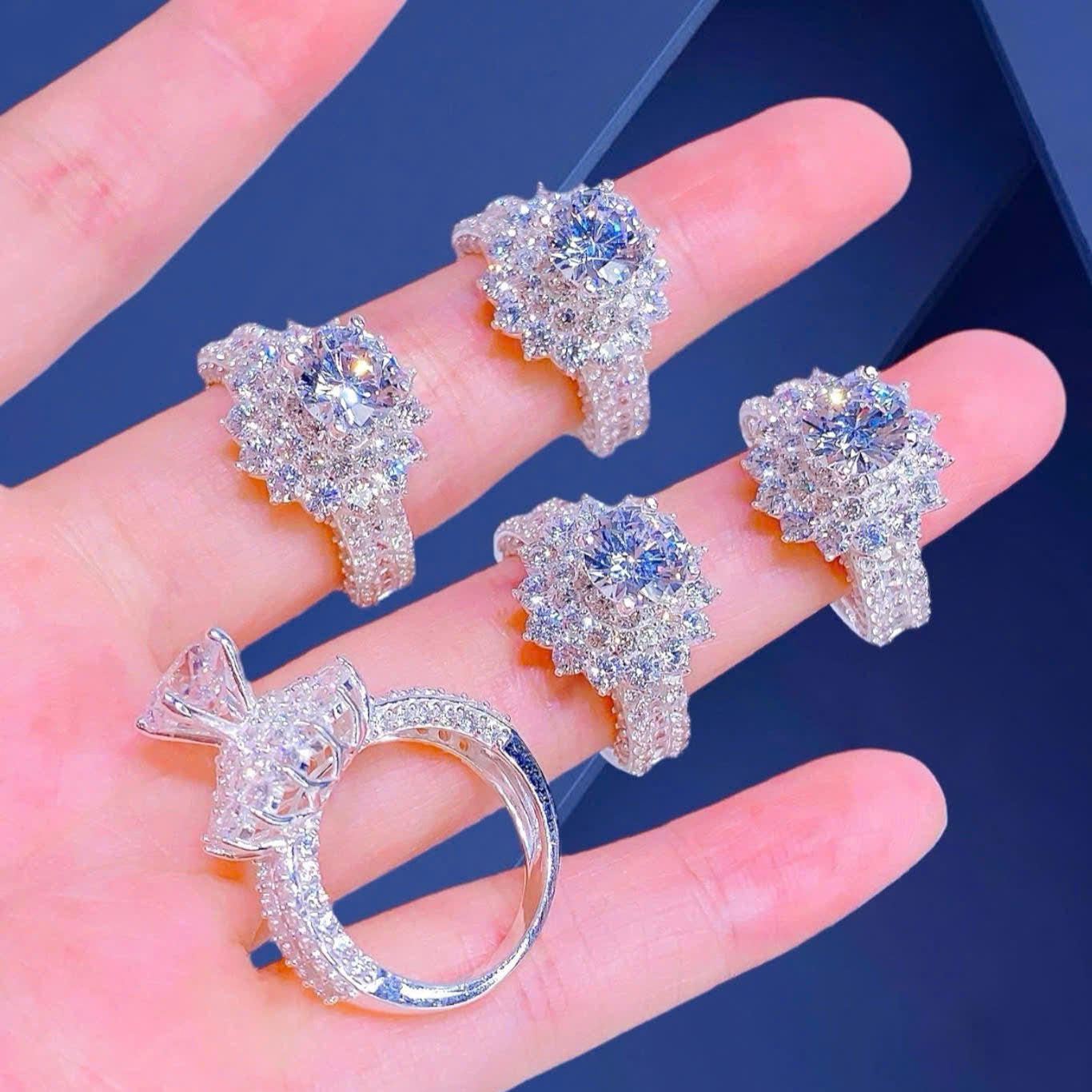 Silver jewelry set with earrings and a ring on a hand against a blue background