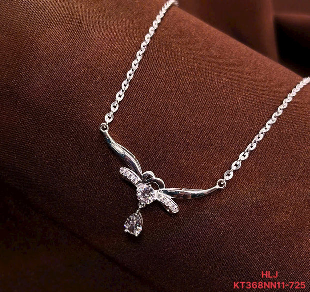 Silver necklace with a delicate pendant on a brown fabric background