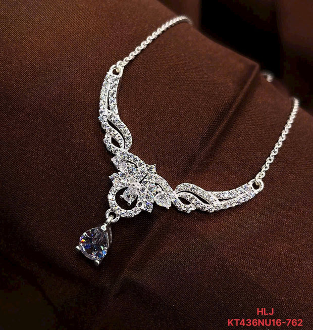 Silver necklace with a heart-shaped pendant on a brown fabric background