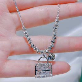 Silver necklace with a lock-shaped pendant held between fingers