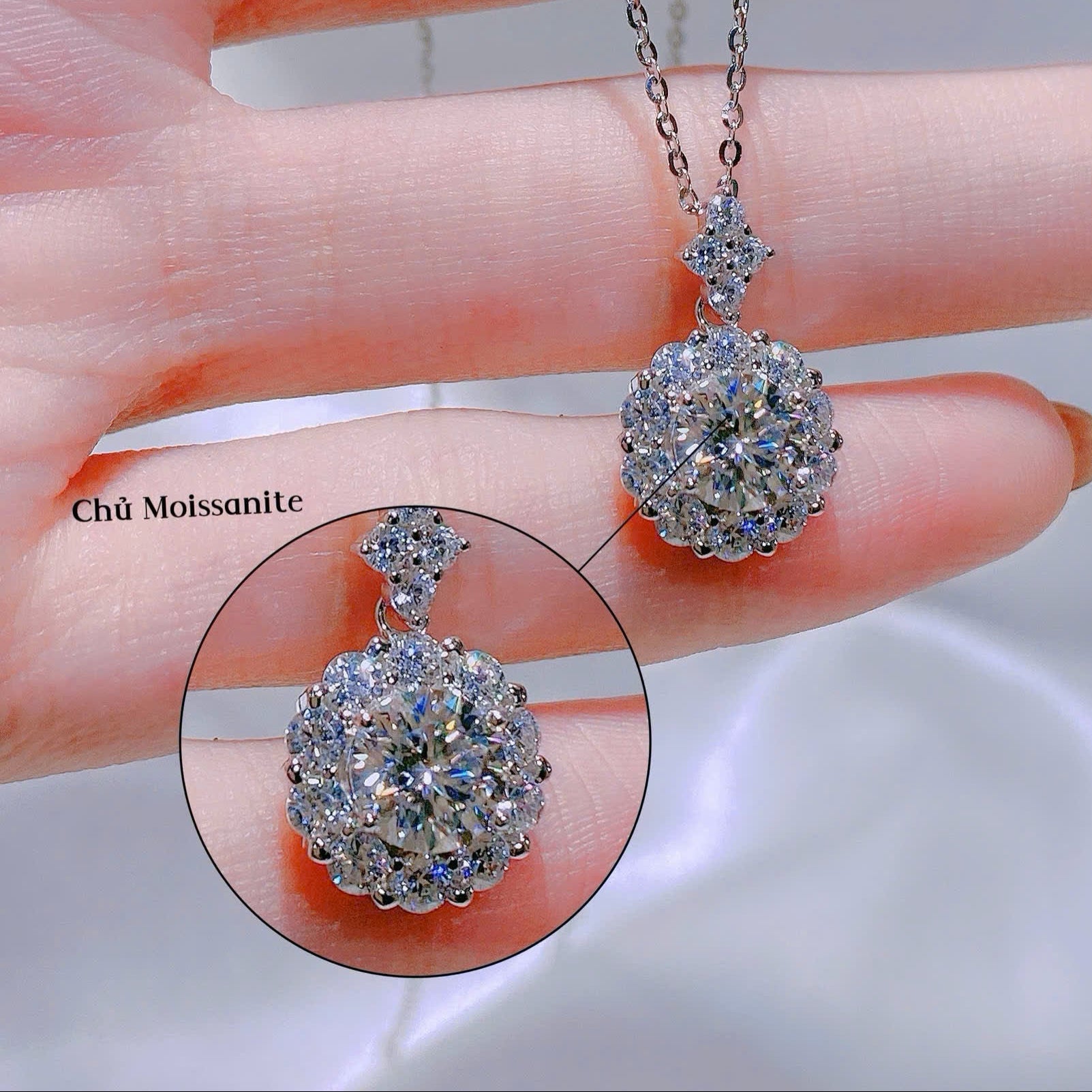 Silver necklace with a pendant held by a hand, close-up view.