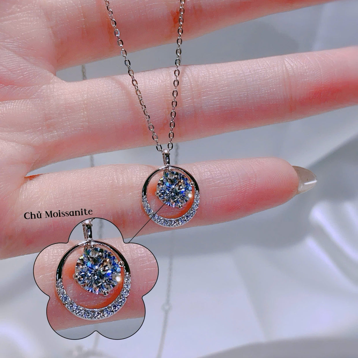 Silver necklace with a pendant held by a hand on a blurred background