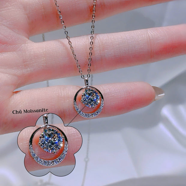 Silver necklace with a pendant held by a hand on a blurred background