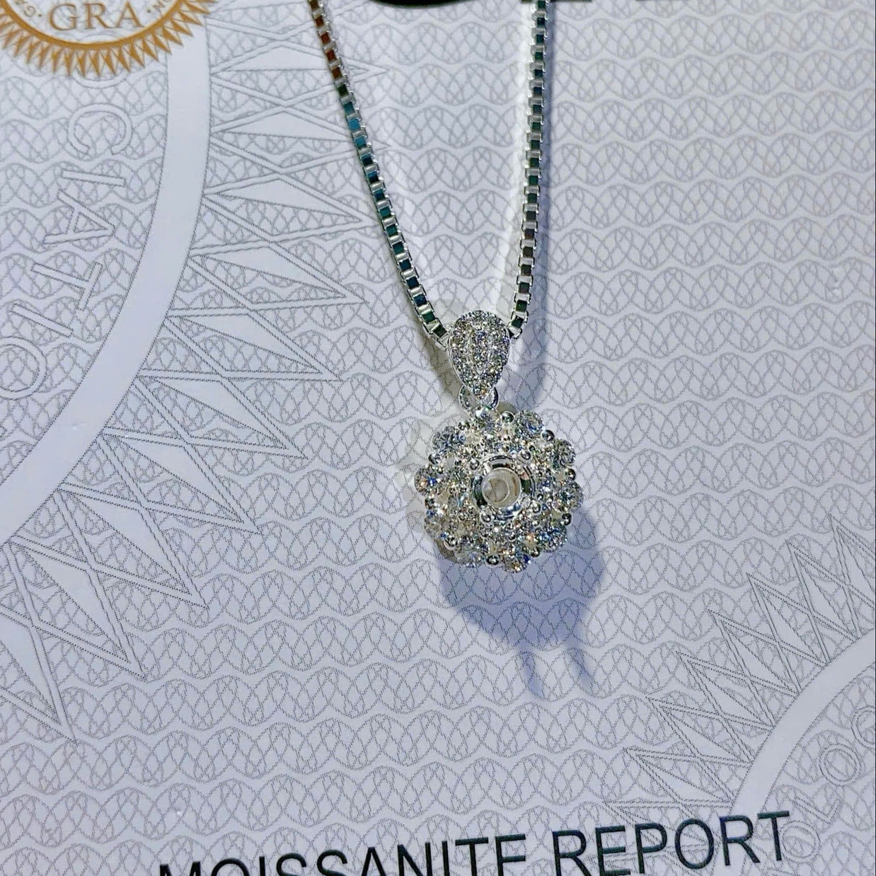 Silver necklace with a pendant on a GRA Moissanite report card.