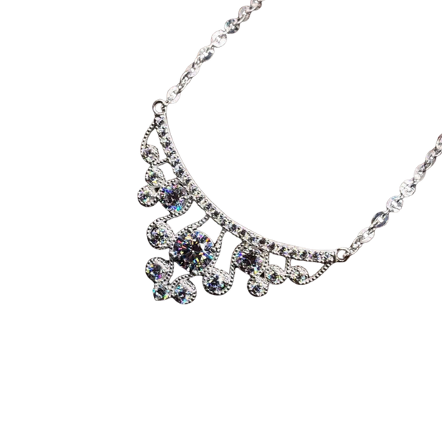 Silver necklace with floral design and clear stones on a white background