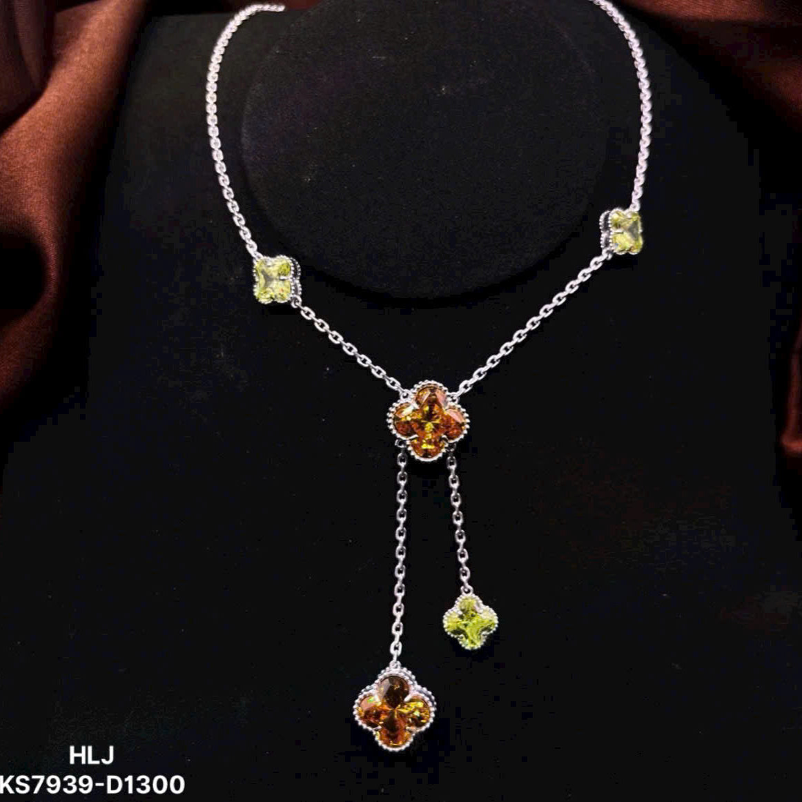Silver necklace with floral pendant and green gemstones on a dark background