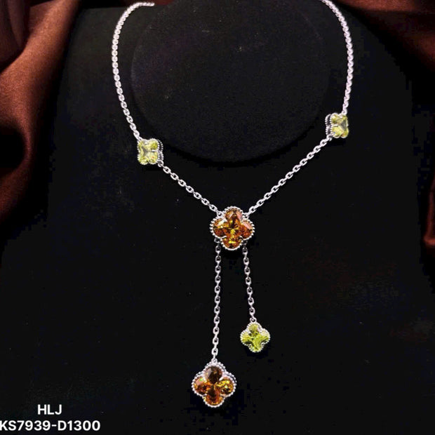 Silver necklace with floral pendant and green gemstones on a dark background