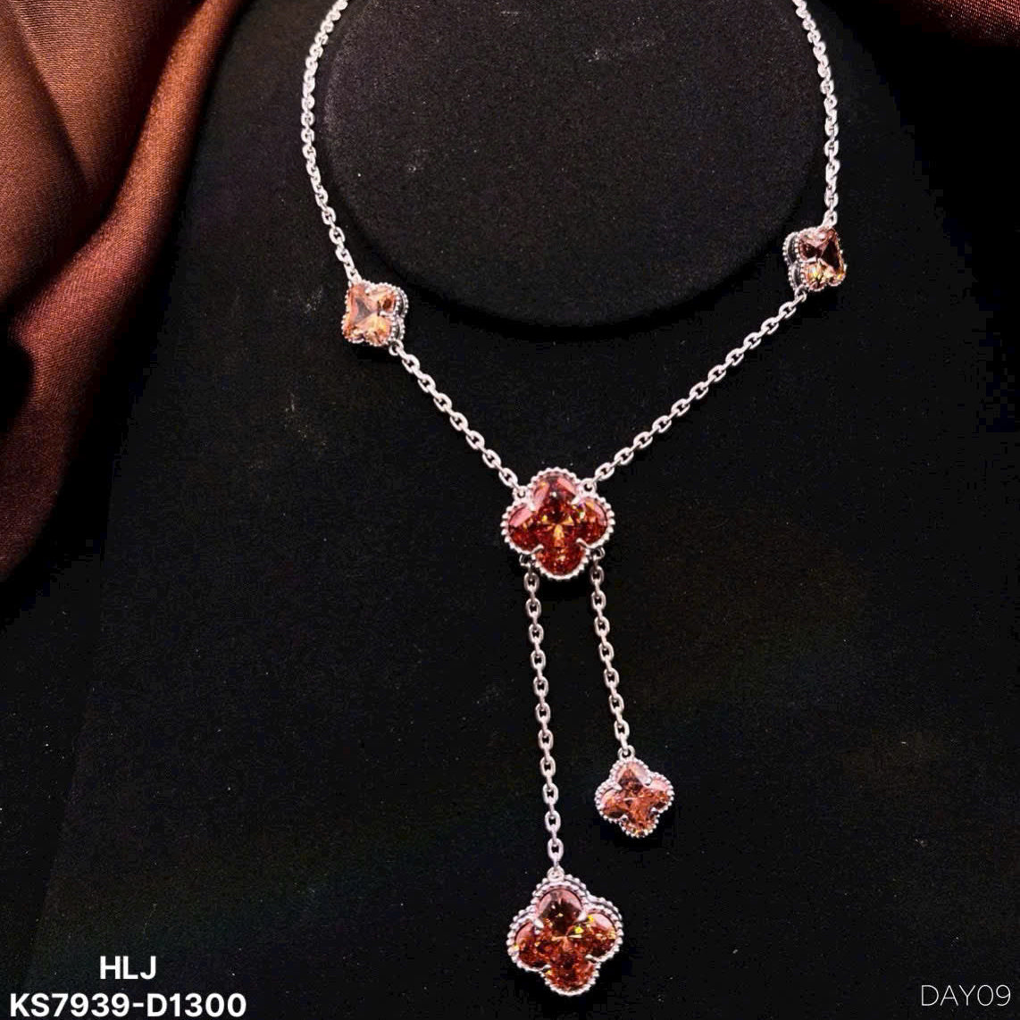 Silver necklace with floral pendants on a black stand