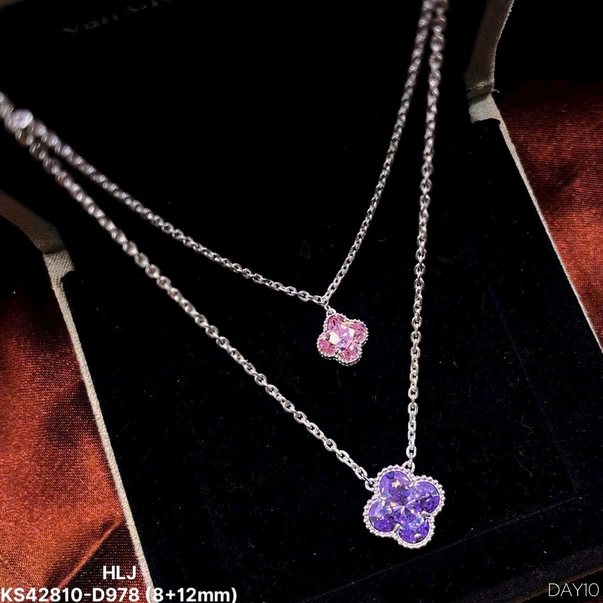 Silver necklace with pink and purple flower pendants on a dark background
