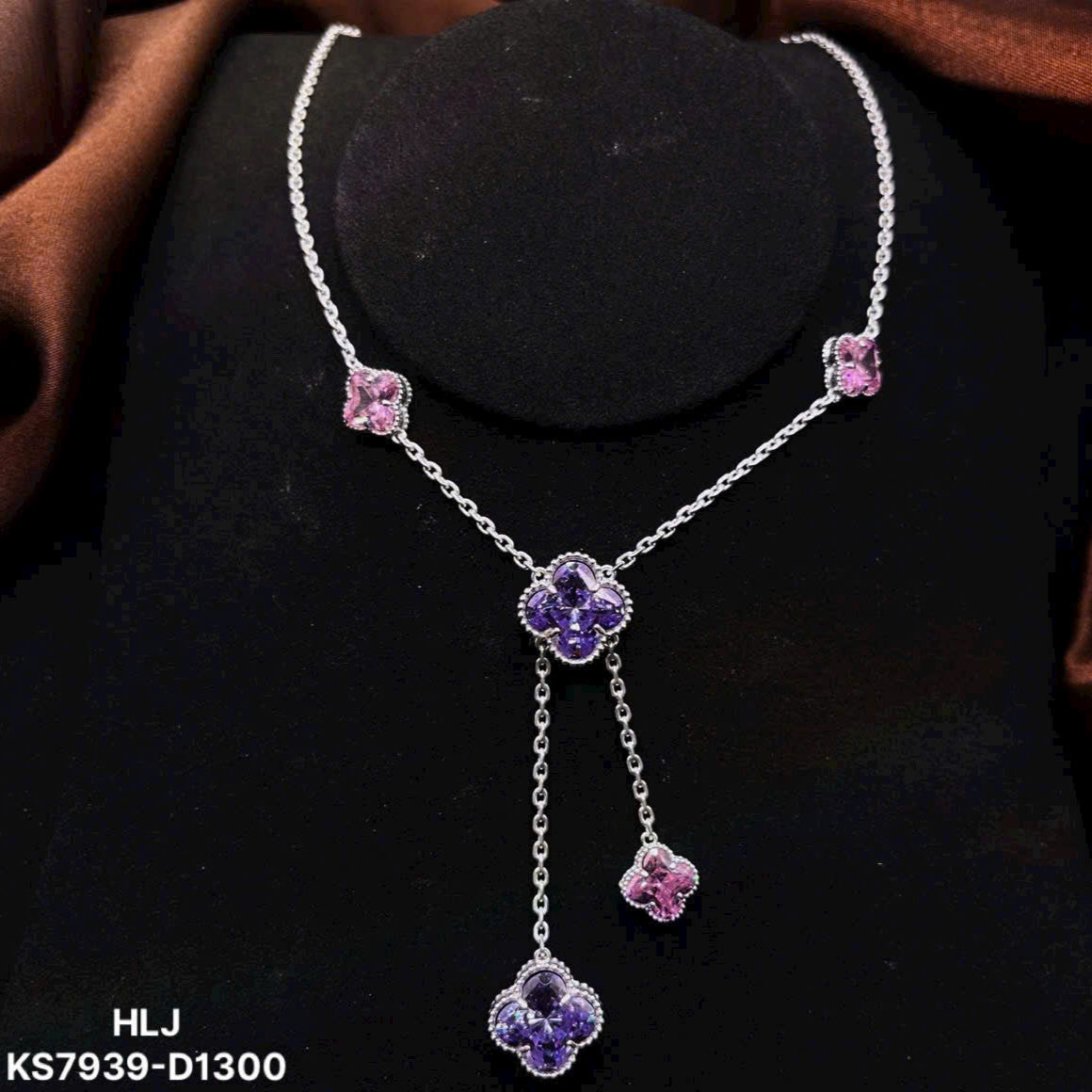 Silver necklace with purple and pink floral pendants on a black stand