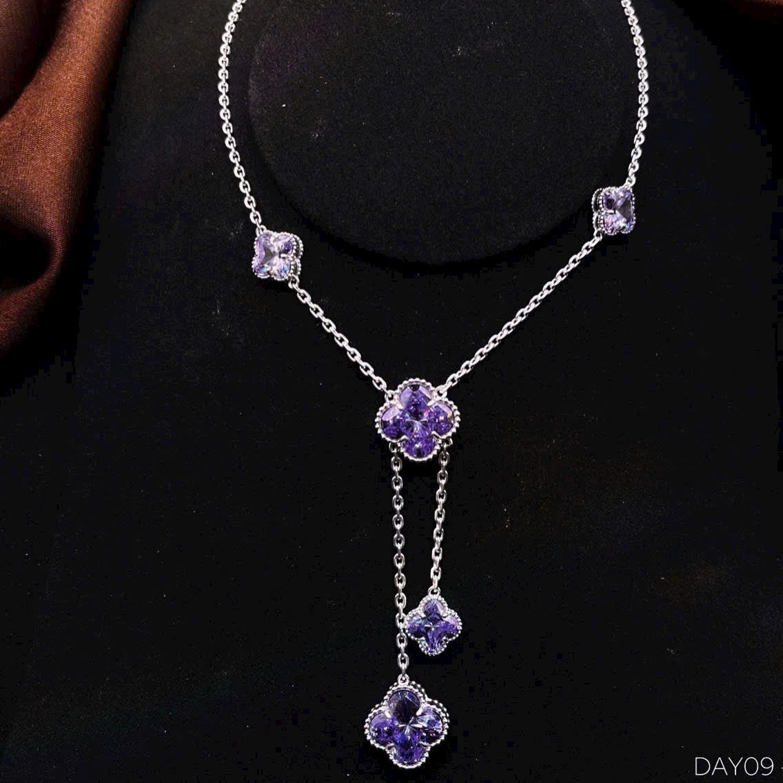 Silver necklace with purple floral pendants on a black background