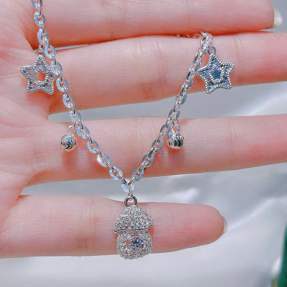 Silver necklace with star-shaped pendants on a hand against a neutral background