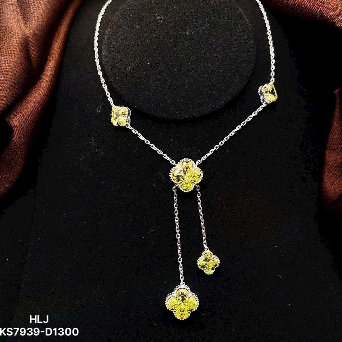 Silver necklace with yellow gemstones on a black stand