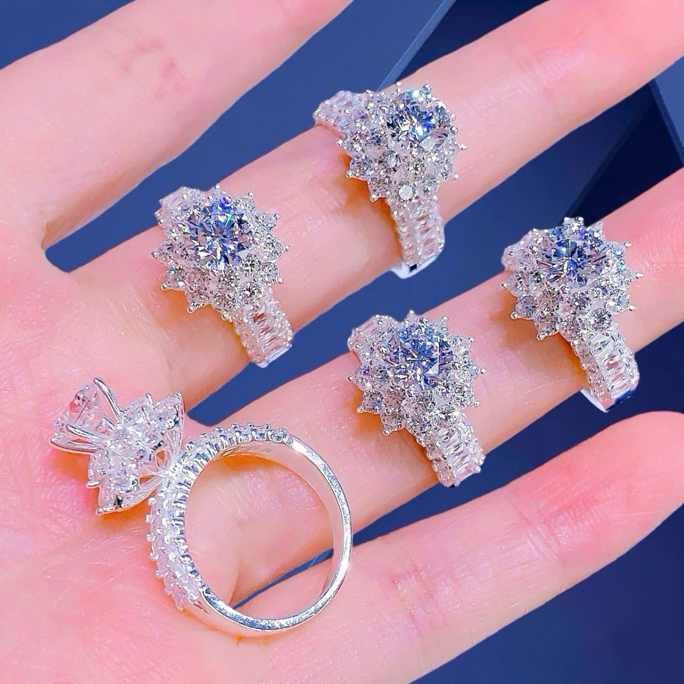 Silver ring and earrings on a hand with a blue background