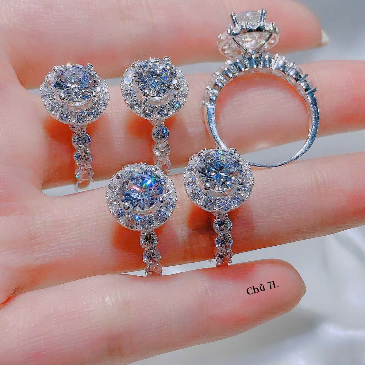 Silver ring and earrings on a hand with visible brand name.