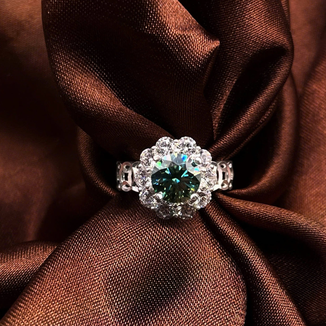 Silver ring with a green gemstone on brown fabric