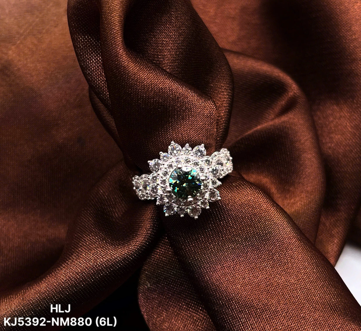 Silver ring with a green gemstone on brown fabric