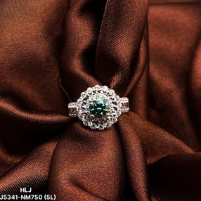 Silver ring with a green gemstone on brown fabric, brand 'HLJ' visible