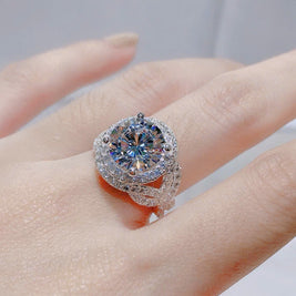 Silver ring with a large blue gemstone on a hand against a neutral background