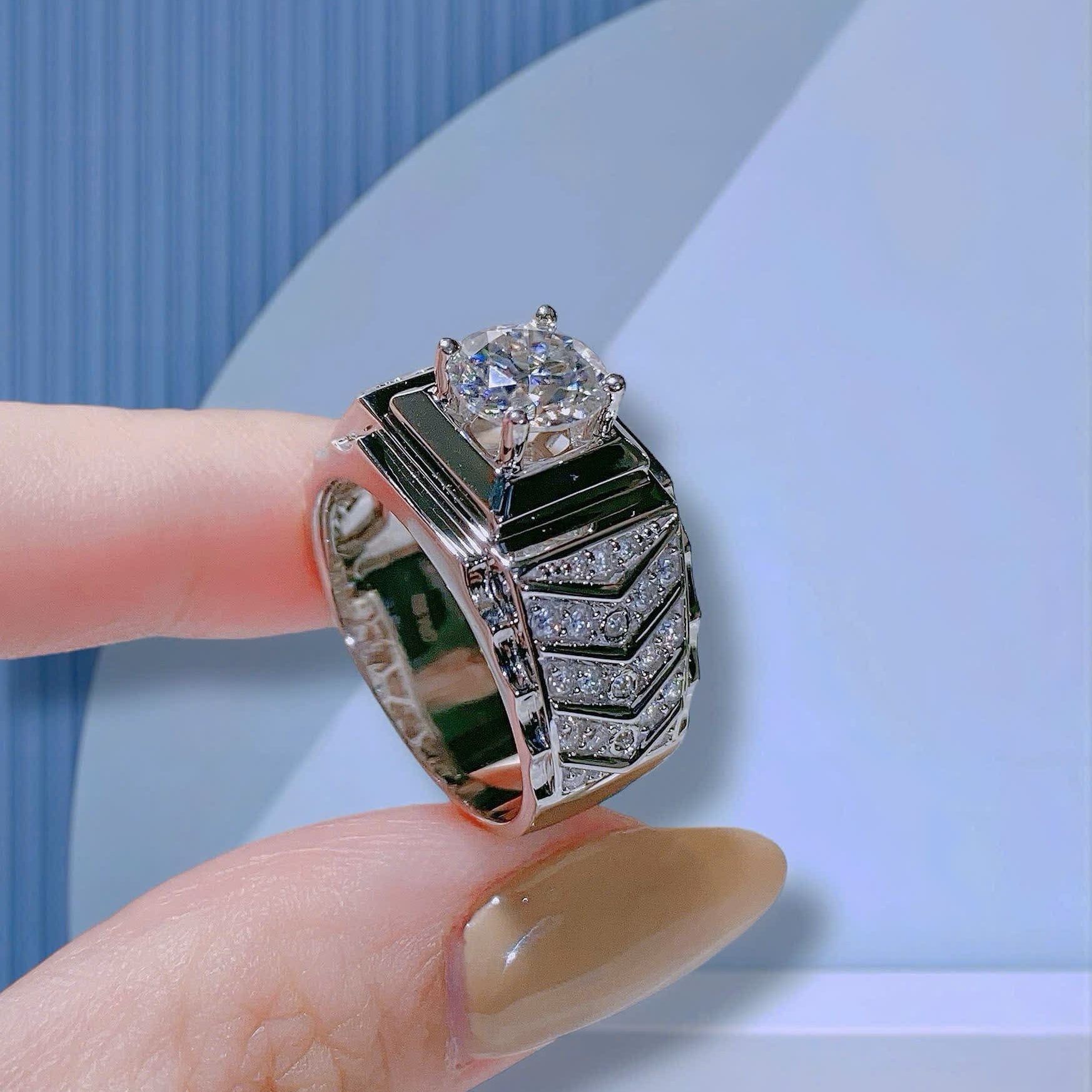 Silver ring with a large diamond on a finger against a light blue background