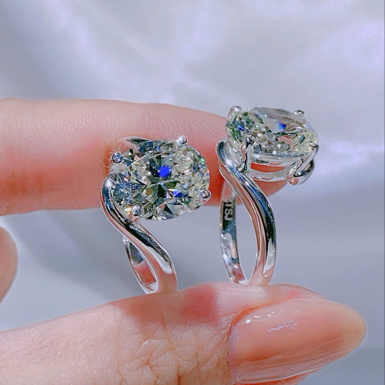 Silver ring with a large gemstone held by a hand against a white background