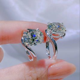 Silver ring with a large gemstone held by a hand against a white background