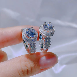 Silver ring with blue gemstone held between fingers against a blurred background